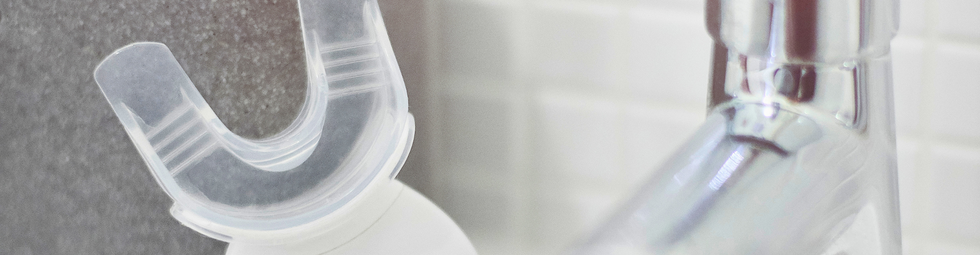Teeth-whitening device beside sink faucet.